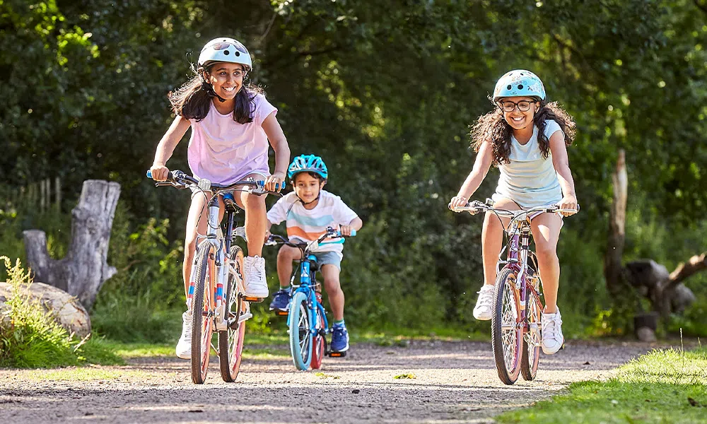 2 girls and a boy riding kids bikes on a summer day in the park