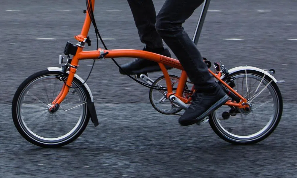 riding a Brompton folding bike close up showing mudguards