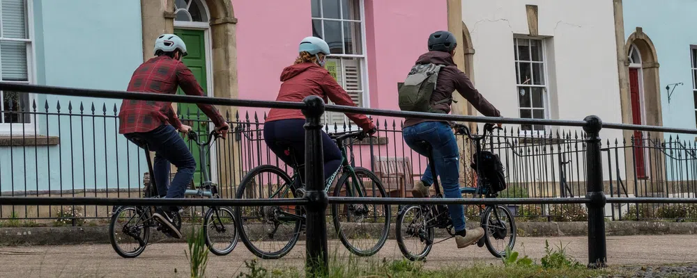 three cyclist riding past coloured houses fronts in Bristol