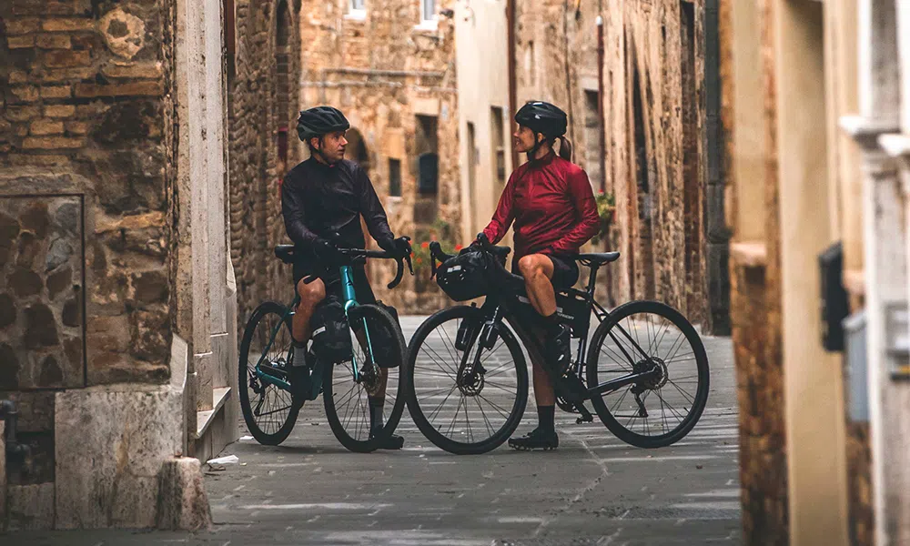 two bike packers on electric gravel bikes in ancient city streets