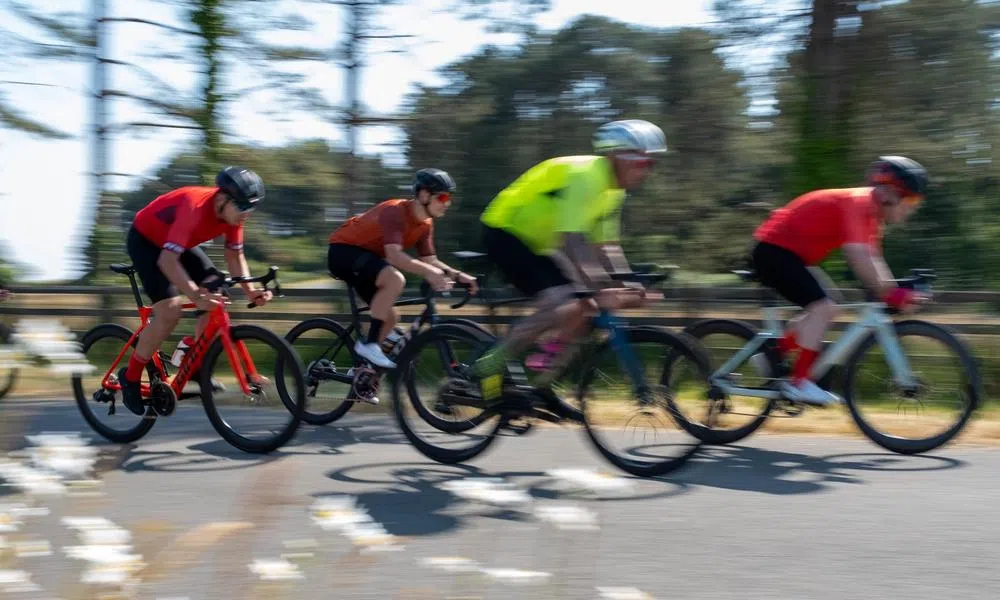 pan shot, road cyclist in a bunch riding fast on a sunny day