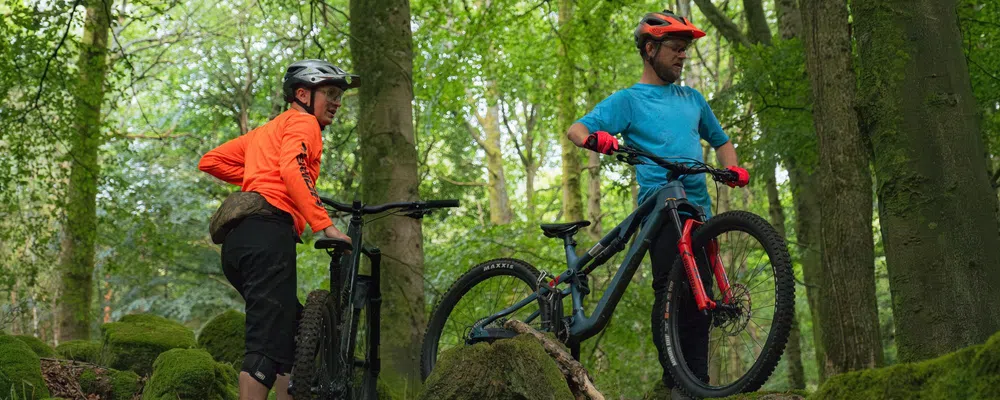 Mountain bikers in the woods checking their lines