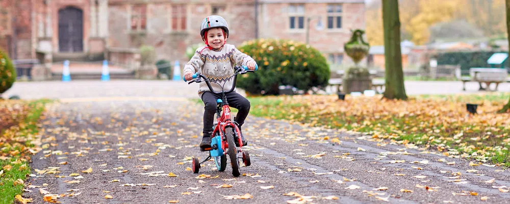 child riding a bike with stabilisers