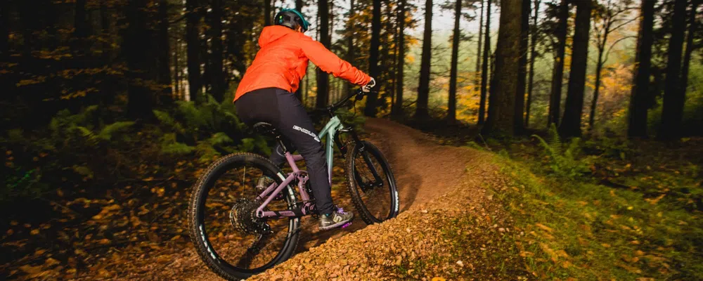 woman riding through the woods on an mtb trail