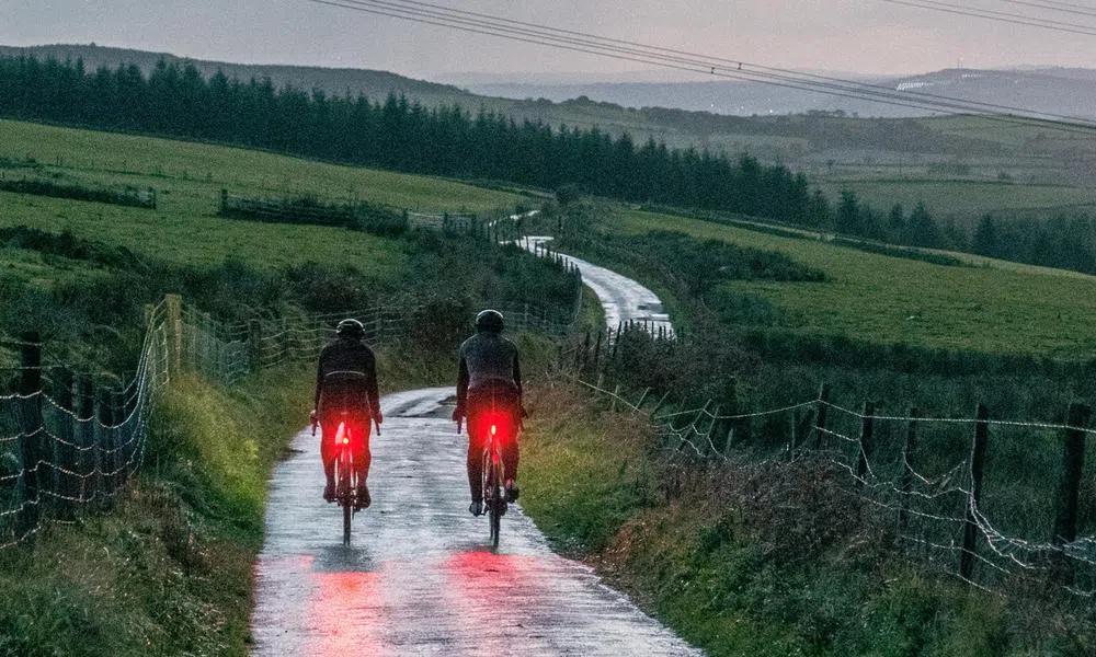 Road cyclists riding at dusk with rear bike lights