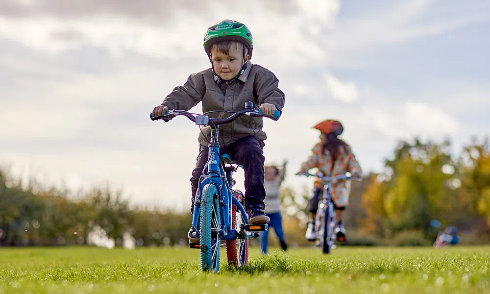 kid riding a 12" wheel bike on an autumn day