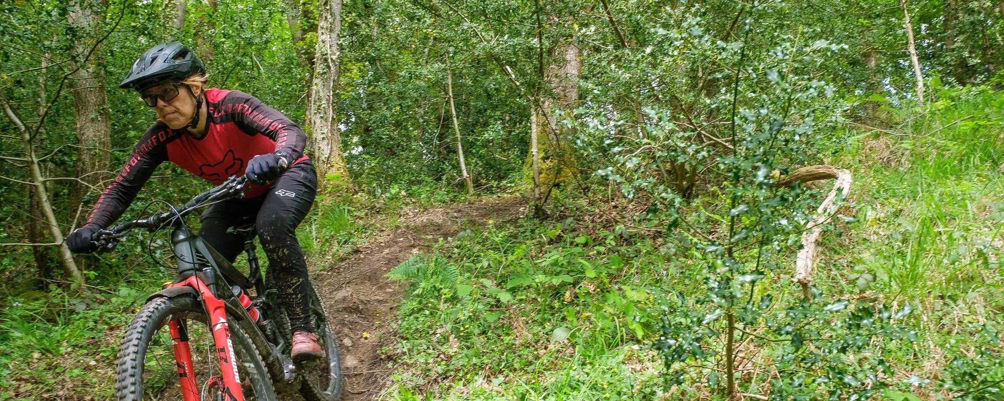 women mountain biker on trail in red fox clothing