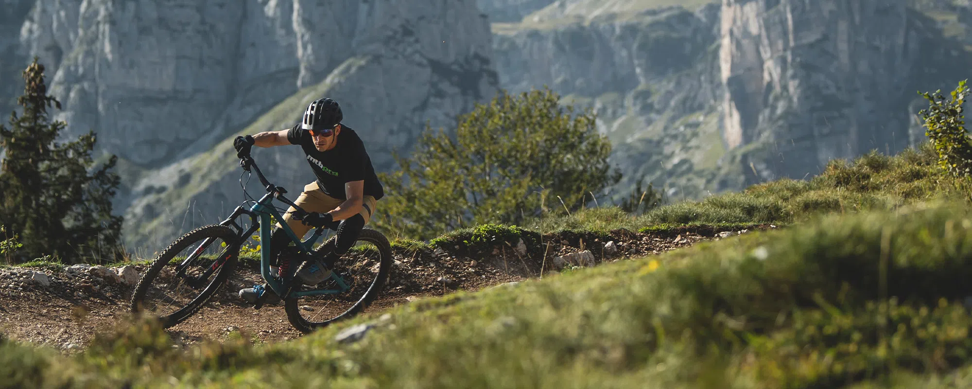 Mountain biker railing a turn in the high alps wearing Dainese gear