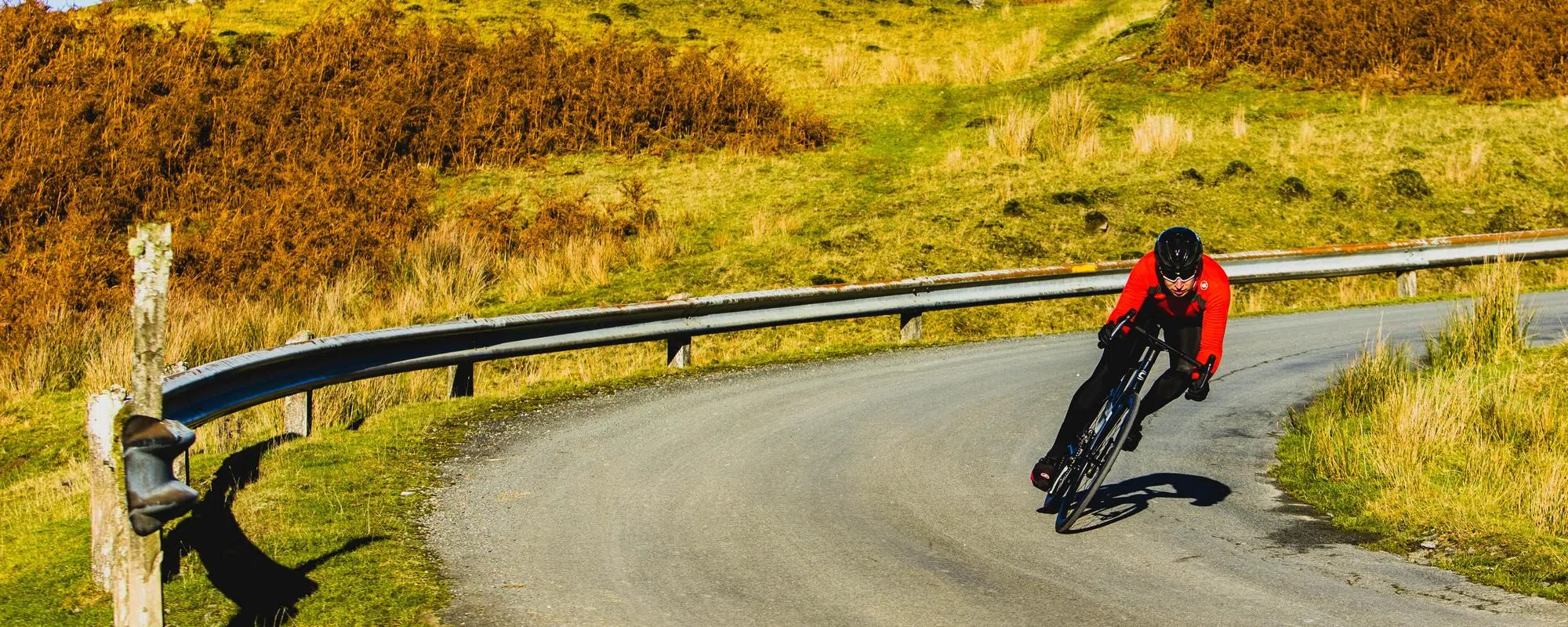 road cyclist in red cornering on hairpin bend