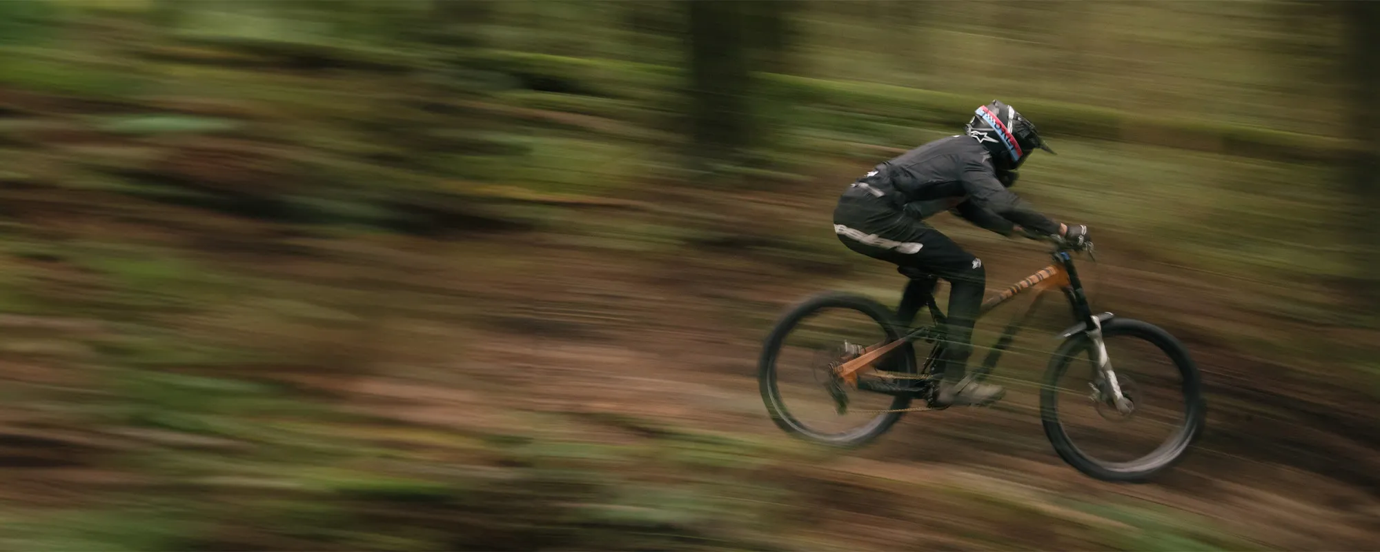 Tegan Cruz riding an NS bike fast in the woods - pan shot