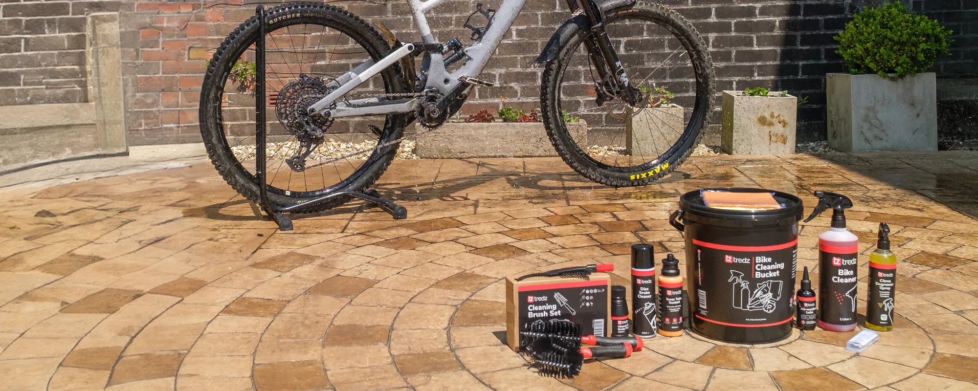 Bike cleaning products by Tredz laid out next to bike