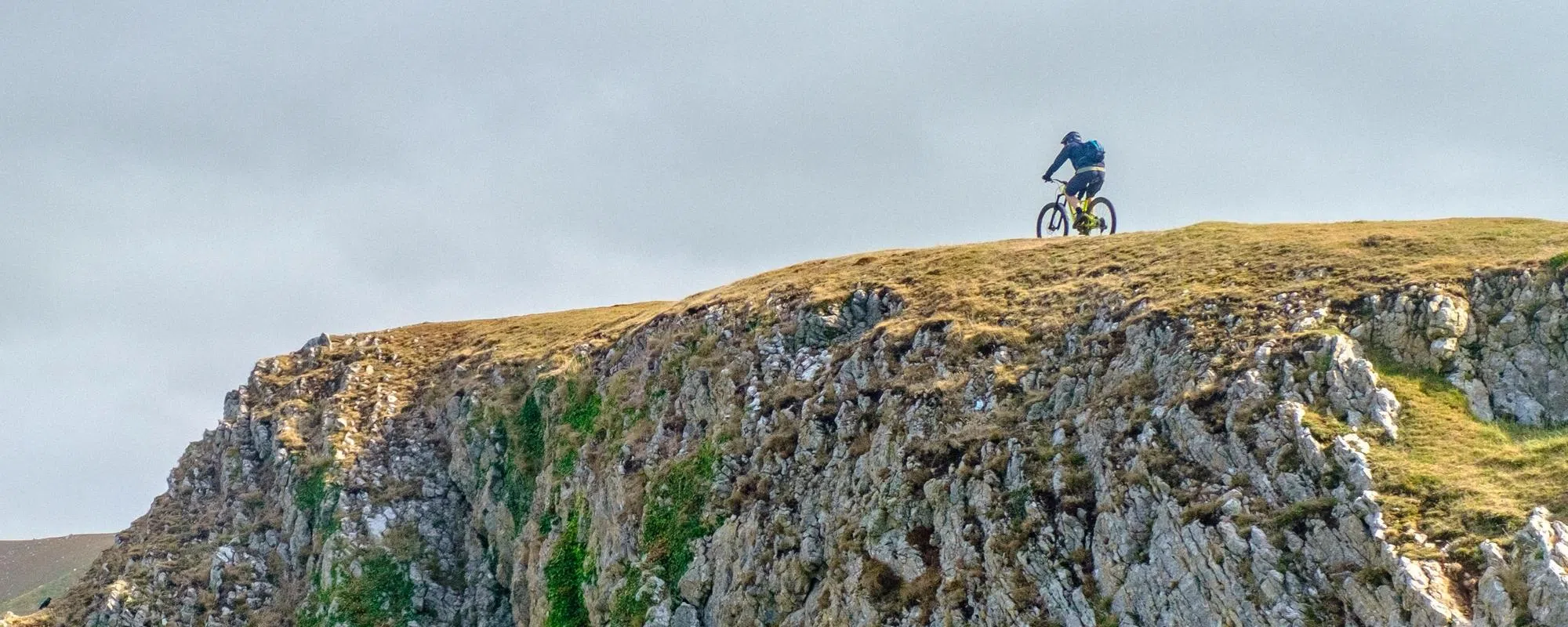 mountain biker riding along the top of a cliff