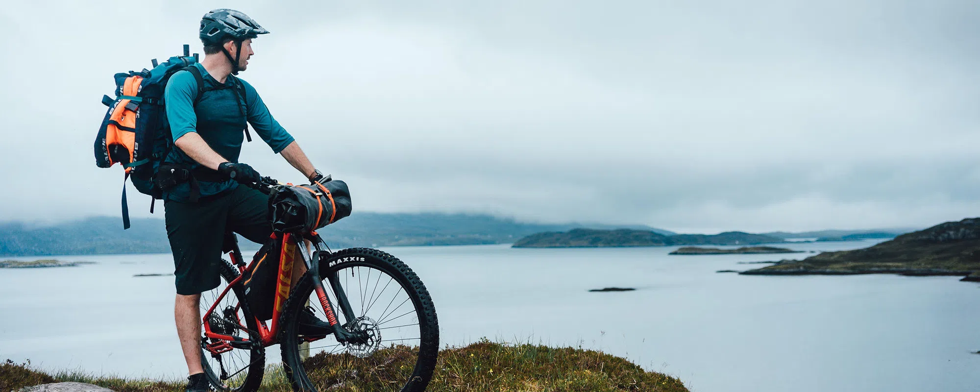 a bikepacker with Ortlieb bags looks out to sea