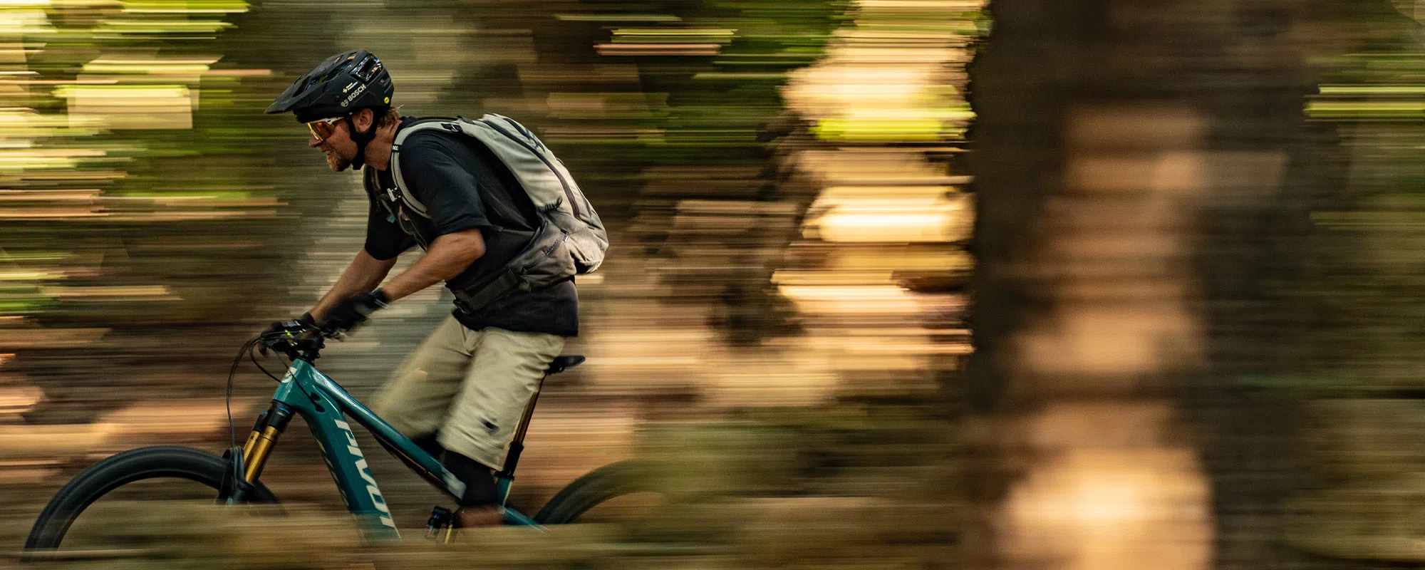 Mountain biker riding a Pivot Shuttle e-bike, summer time pan shot in the woods