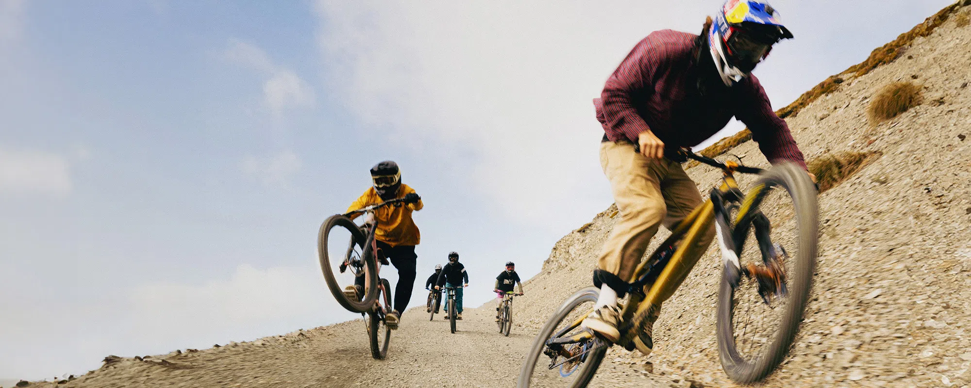 5 mountain bike riders on Specialized Status ride down a gravel track