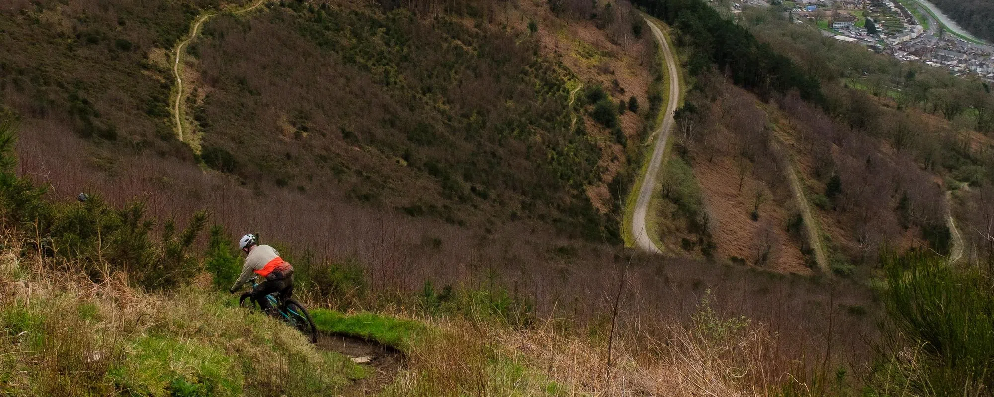 mountain biker descending with trail in the background