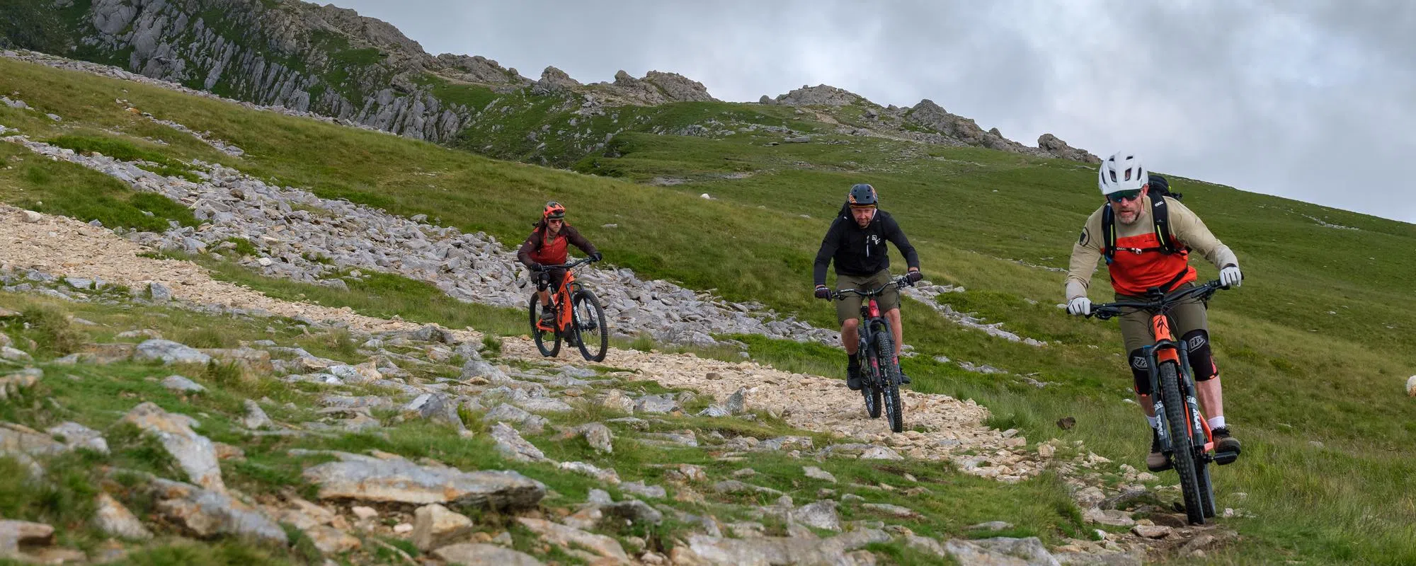 three mountain bikers descending a rocky mountain trail