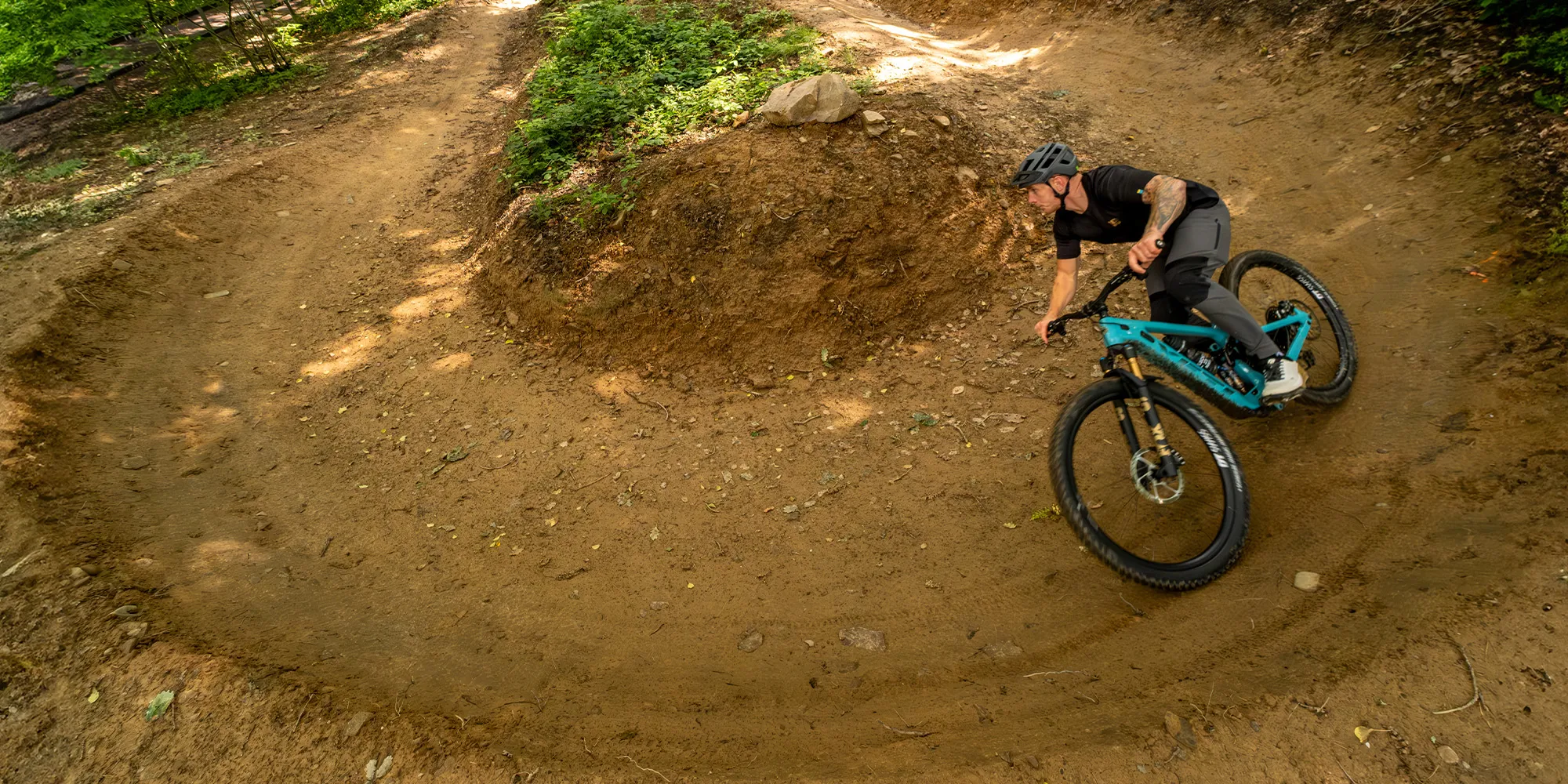 Riding the Yeti MTe around a 180 berm in the woods
