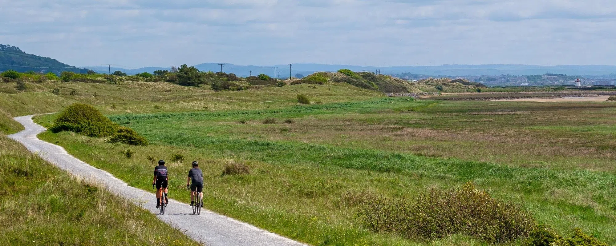 two cyclist riding along a gravel path in wide open estury border