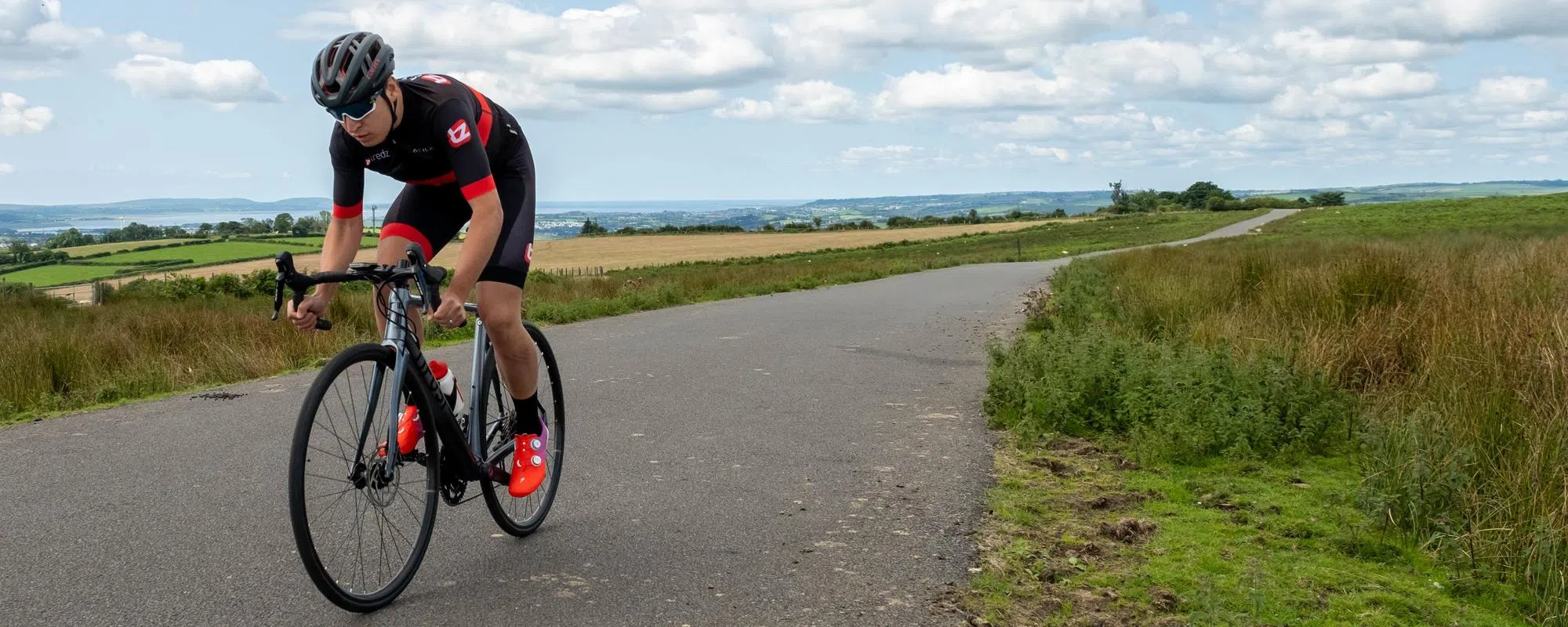 road cyclist riding a Tifosi bike on a quiet country road over the welsh hills