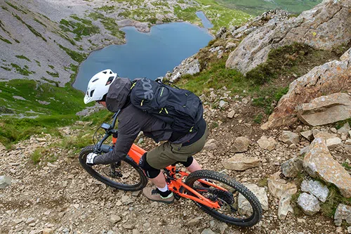 mountain biker riding above lake 