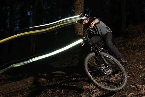 mountain biker riding with helmet light and bar light trails