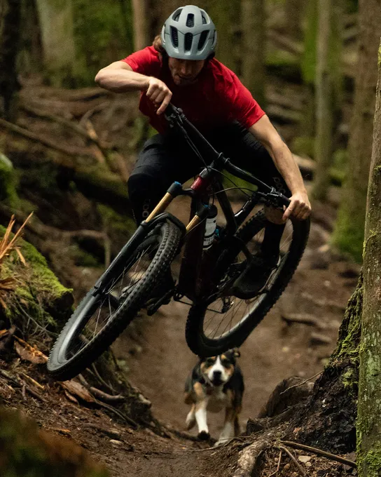 Man riding a mountain bike with Bontrager wheels and a dog following
