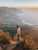 a man standing on top of a rock cliff overlooking a town and sea