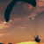 a man about to paraglide off a cliff during a sunset 