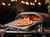 Ooni pizza oven with fire inside and a cooked pizza being taken out of the oven