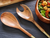 wooden serving spoons next to a metal salad bowl