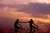 couple holding hands and riding a bike at sunset 