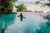 woman with sunhat on in a open pool overlooking the beach