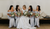 bride with four bridesmaids in blue dresses sat on a bench