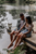 a happy couple sitting on the edge of a river dock