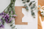 poem invitation on table with leaves and purple flowers