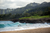 people swimming in the sea next to a green cliff in hawaii