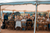 Guests sitting next to a long table inside a wedding marquee