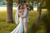 Bride and groom stand between trees, looking at each other