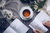 book on a grey cloth surrounded by tea and flowers