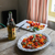 fresh tomato salad in a dish next to olive oil and a chopping board