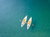 couple staring at the sky in canoes in a clear sea