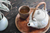 white tea with wooden handle next to a ceramic cup