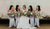 a bride and her bridesmaids sitting and holding bouquets 