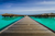 a pier across a beach towards huts in bali