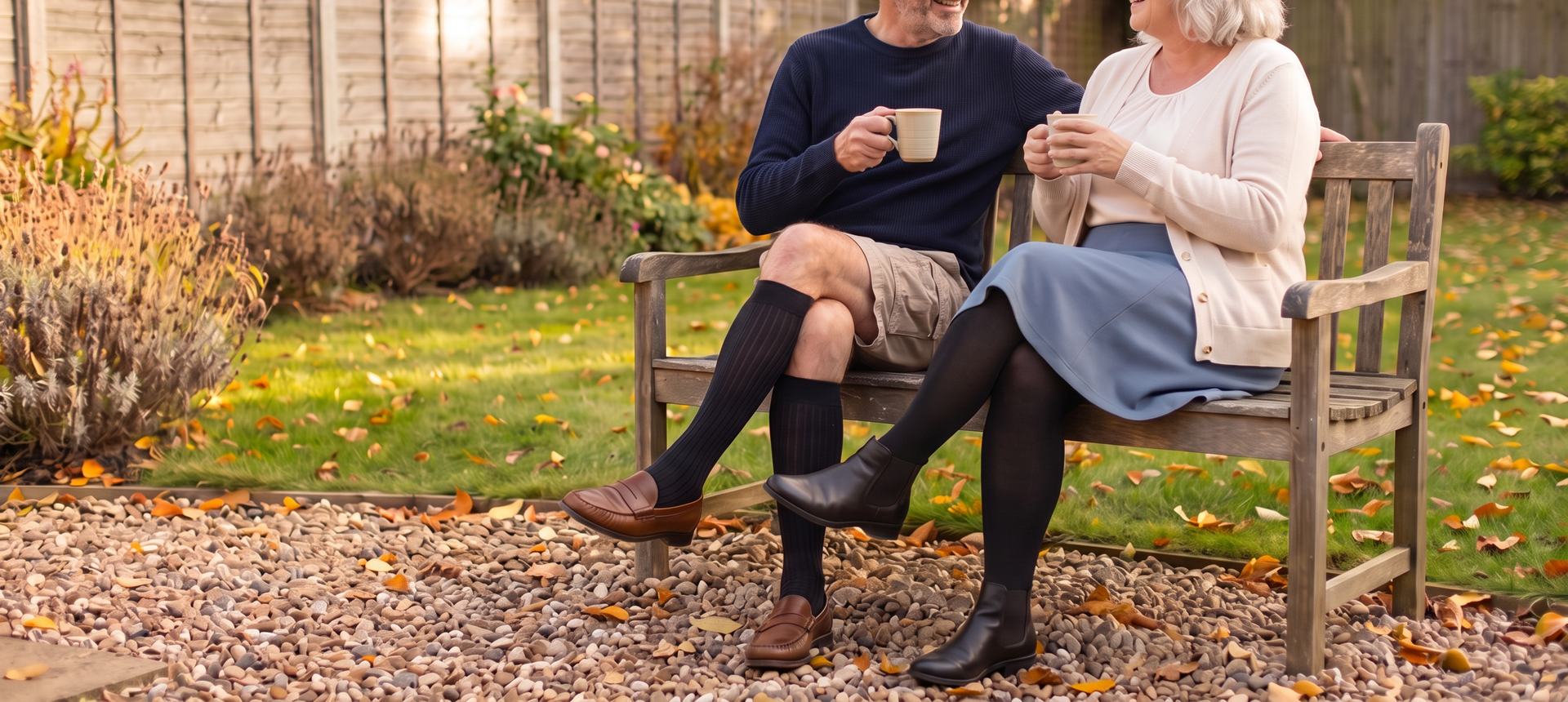 Couple on a garden bench in autumn wearing JOBST compression: men's black knee-highs and women's black opaque tights