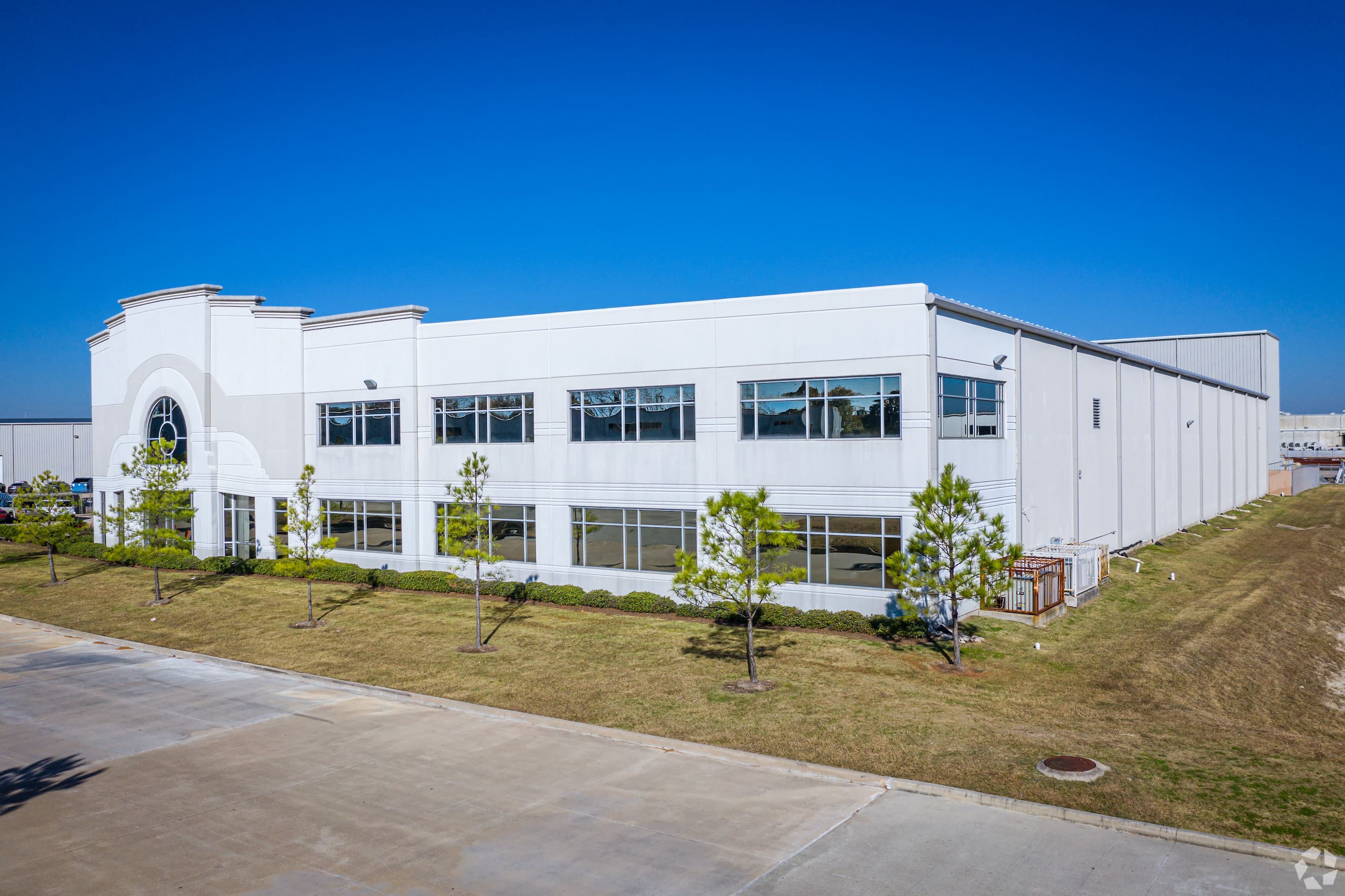 The front of a large warehouse, with a grand frontage and several windows under a blue sky.