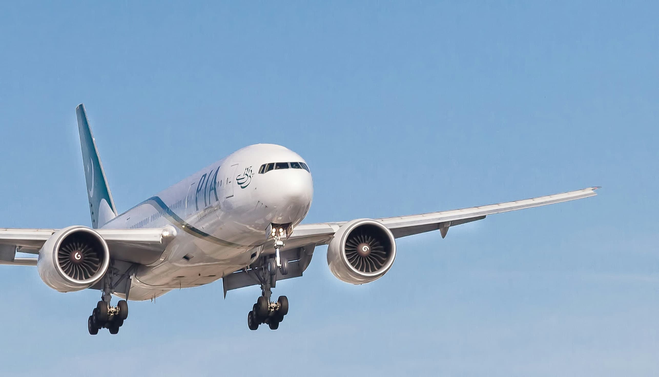 A commercial aircraft in flight against a blue sky.