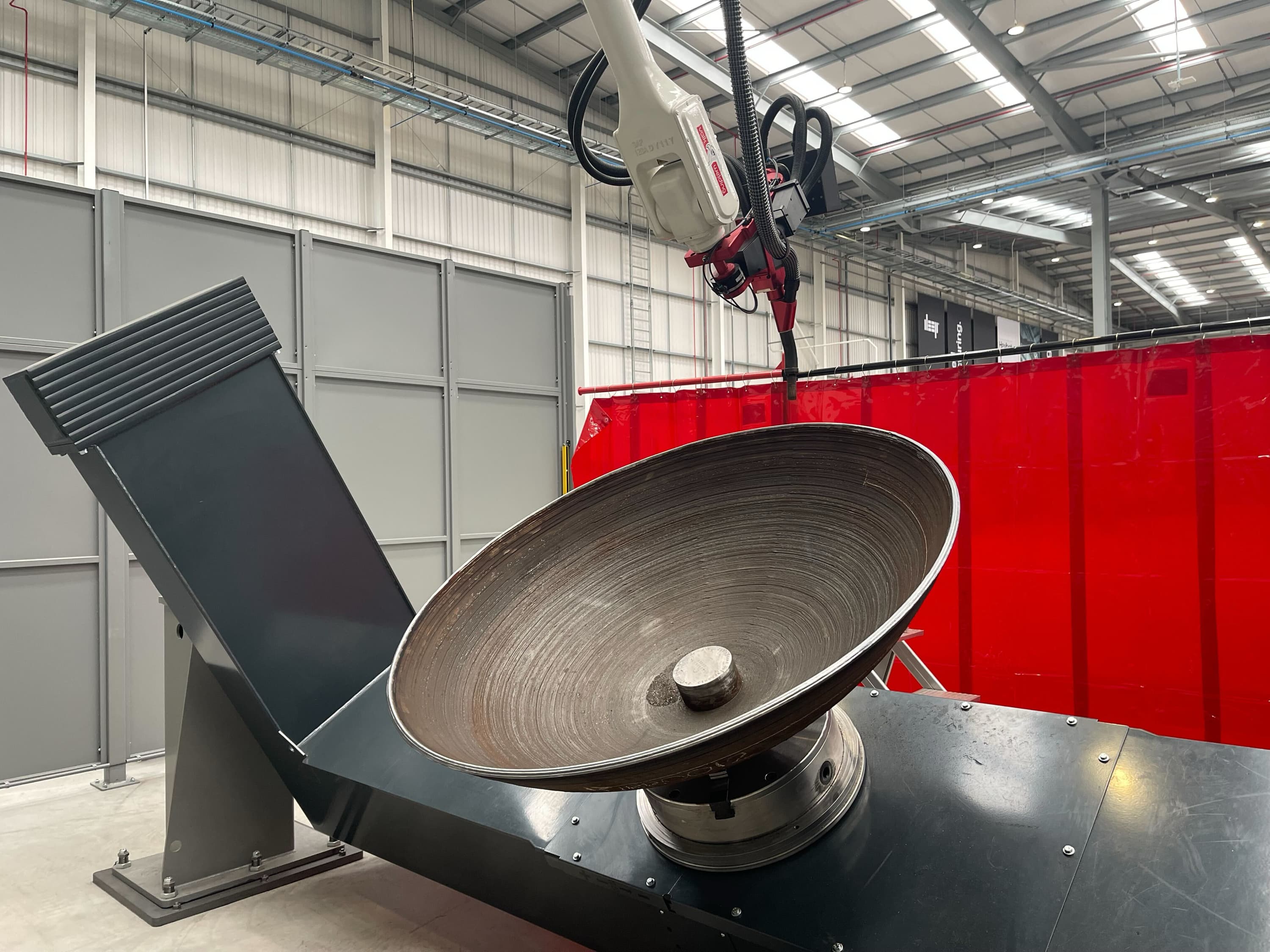A metal 3D printed hemisphere on a two axis manipulator with WAAM robott.