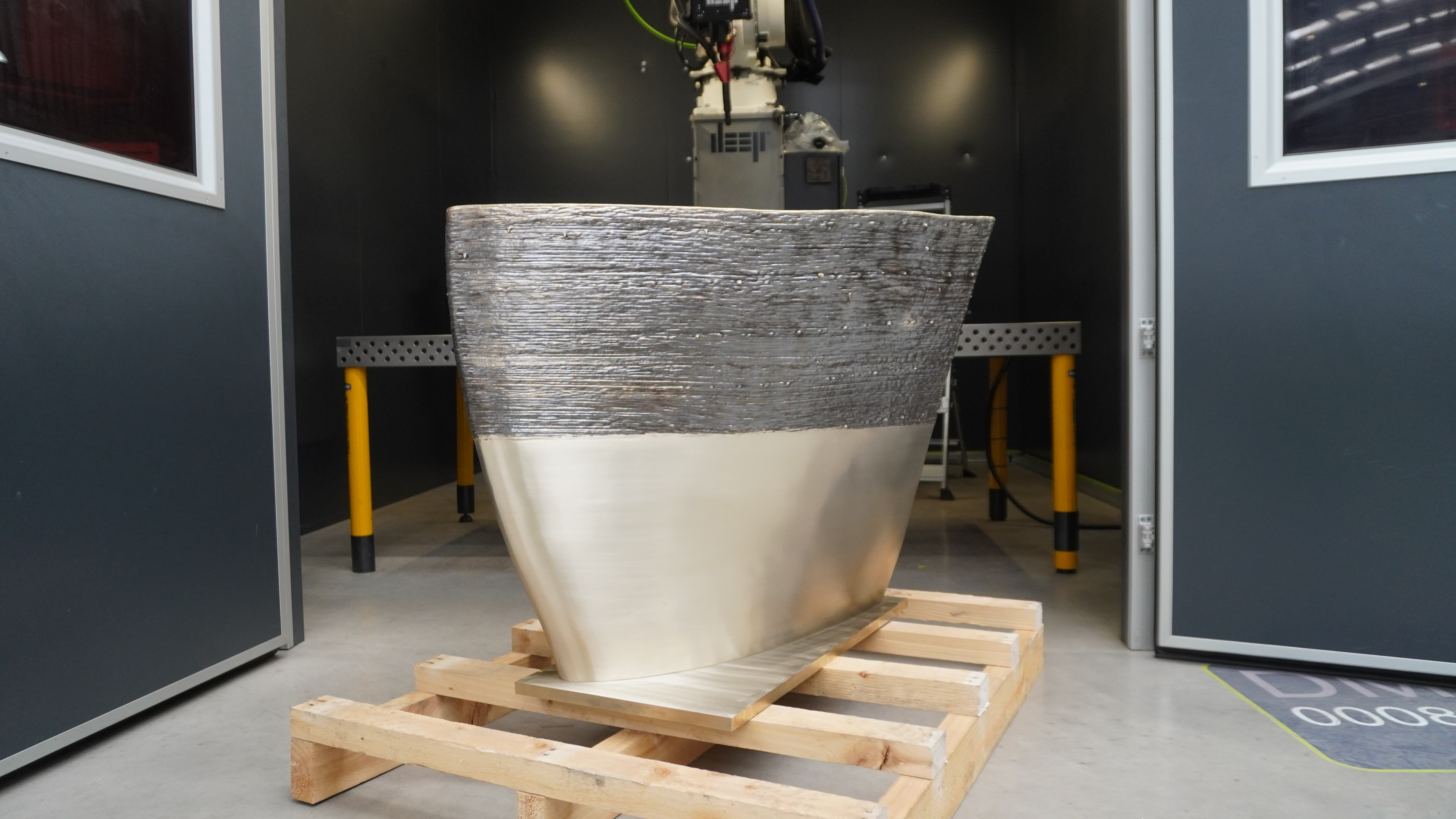 A golden metal 3D printed sector of a propeller blade, half machined and half as-printed